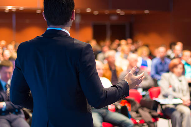 Stock photo of a speaker standing in front of a group.